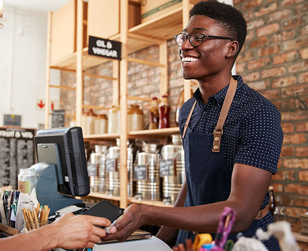 A male barista accepting card payments using SymPay's POS systems